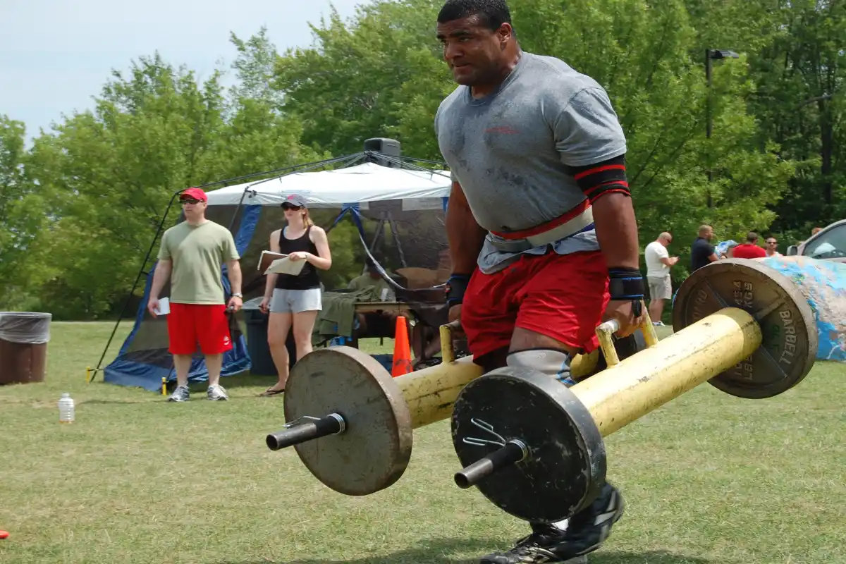 Man performing a farmer’s walk, showcasing grip strength, forearm engagement, and core stability.